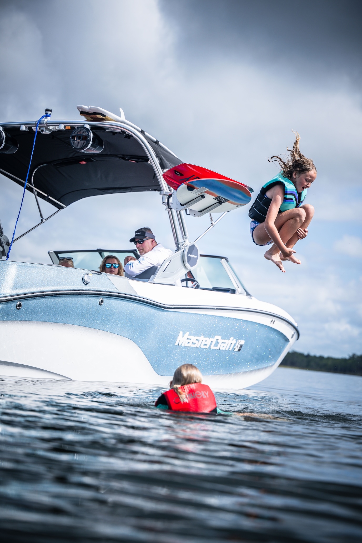 Child wearing lifevest doing a cannonball into lake.